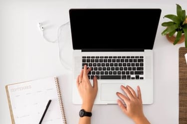 laptop on desk next to notebook