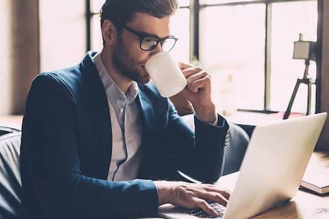 man on laptop drinking coffee